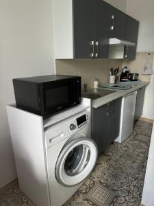 a kitchen with a washing machine and a microwave at Studio Le Mansart au pied du Château Insead in Fontainebleau