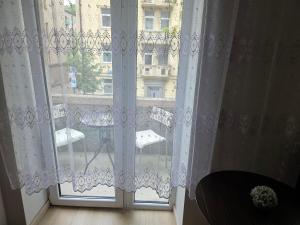 - une fenêtre avec des rideaux blancs et une vue sur un bâtiment dans l'établissement Kambarys su balkonu ir didele lova Kauno centre #6, à Kaunas