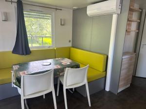 une chambre avec une table, des chaises et un canapé jaune dans l'établissement Camping Le Ruisseau, à Saint-André-de-Seignanx