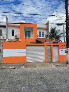 una casa arancione e bianca con due porte garage di Casa para temporada - São João 2024 a Campina Grande