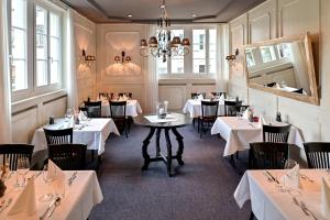 een restaurant met witte tafels en stoelen en een kroonluchter bij Hotel Zofingen in Zofingen