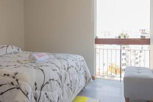 een wit bed in een kamer met een groot raam bij Departamento confortable en San Borja in Lima