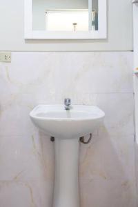 een witte badkamer met een wastafel en een spiegel bij Departamento confortable en San Borja in Lima