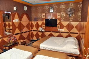 a bedroom with two beds and a tv on the wall at Hotel Shri Swarna's Palace - A Business Class Hotel in Tiruchchirāppalli