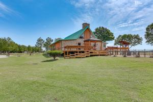 a large wooden house with a green roof in a field at Hornersville Vacation Rental with Private Pond! 