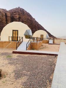 dwie kopuły na pustyni z górą w tle w obiekcie Omar Camp Wadi Rum w mieście Disah