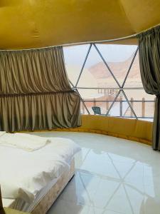 a bedroom with a bed and a large window at Omar Camp Wadi Rum in Disah