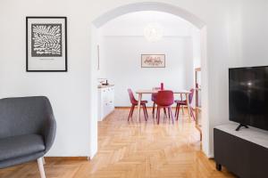 een woonkamer met een tafel en stoelen en een televisie bij Pangrati Gardens Apartment by Athenian Keys in Athene