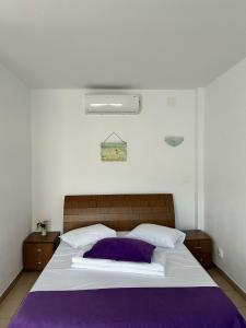 a bedroom with a large bed with purple and white pillows at Vilele Bianca in 2 Mai