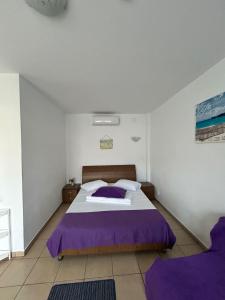 a bedroom with a large bed with purple sheets at Vilele Bianca in 2 Mai