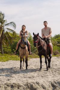 a man and woman riding horses on the beach at Paraíso Natural Ecohotel in San Bernardo del Viento