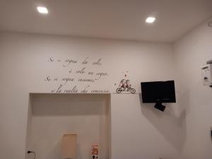 a wall with a writing on the wall with a tv at La casa di Orso in Velletri