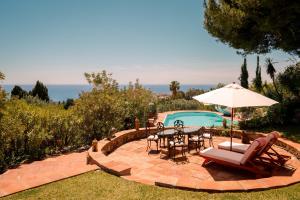 a patio with a table and chairs and a pool at 7,000 sqm Luxurious Villa with Panoramic Sea Views Multiple Gardens & Two Pools in Benalmádena