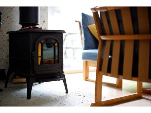 estufa negra en una sala de estar junto a una silla en MORIHAKU - Vacation STAY 34533v en Kutsukake