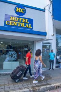 un par de personas con equipaje caminando frente a una terminal del hotel en Hotel Central, en Sincelejo