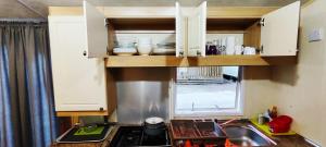 una cucina con armadi bianchi, lavandino e finestra di MareBlue Mobilhomes & Caravans a Lido di Spina