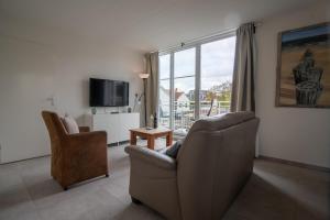 sala de estar con sofá, silla y TV en Appartementen Zee Domburg, en Domburg