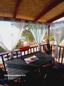 a table on the porch of a house with curtains at Mobile home Relax in Klenovica