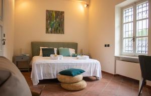 1 Schlafzimmer mit einem Bett mit einem Tisch und 2 Fenstern in der Unterkunft Villa Magna with pool Alba Hills in Govone