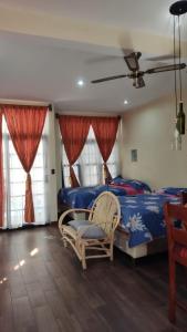 um quarto com uma cama, uma cadeira e janelas em Apartamento Jacob em San Pedro La Laguna