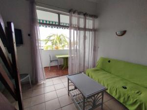 ein Wohnzimmer mit einem grünen Sofa und einem Tisch in der Unterkunft Le cocotier in Les Trois-Îlets