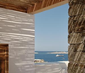 een kamer met een stenen muur en uitzicht op de oceaan bij Boheme Mykonos Town - Small Luxury Hotels of the World in Mykonos-stad