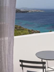 een tafel en een stoel op een balkon met uitzicht op de oceaan bij Boheme Mykonos Town - Small Luxury Hotels of the World in Mykonos-stad