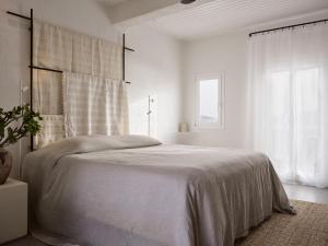 een witte slaapkamer met een groot bed en een raam bij Boheme Mykonos Town - Small Luxury Hotels of the World in Mykonos-stad