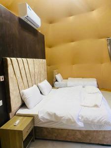Omar Camp Wadi Rum في Disah: سريرين توأم في غرفة مع تلفزيون على الحائط