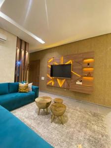 un salon avec un canapé bleu et une télévision dans l'établissement Impérial appartement 3BR, à Harhoura