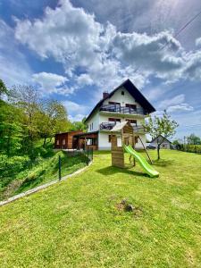 a house with a slide in front of a yard at Kuća za odmor Maklen in Brod Moravice