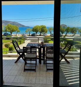 uma mesa e cadeiras numa varanda com vista para o oceano em Seashore Happiness Apartments em Porto Rafti