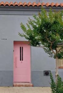 Una puerta rosa en un edificio blanco con un árbol. en La casa de Rosita, en San Pedro