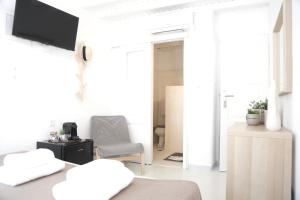 Habitación blanca con cama y silla en Whitelist Studios in Mykonos Town en Mykonos ciudad