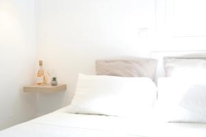 Cama blanca con almohadas blancas y estante en Whitelist Studios in Mykonos Town en Mykonos ciudad