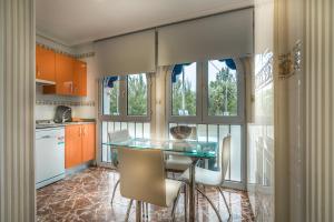 uma cozinha com uma mesa de vidro e algumas janelas em Apartamentos Las Brisas em Santander