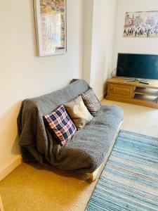 a couch sitting in a living room with a tv at Victoria Rooms in Manchester