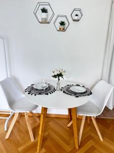 a dining room table with white chairs and a white wall at Stilvolles Apartment - Unteraching in Unterhaching