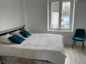 Un dormitorio con una cama con almohadas azules y una ventana. en Maison FAM'APA, en Vittel