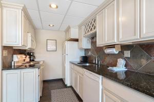 une cuisine avec des armoires blanches et des comptoirs noirs dans l'établissement Beaver Run Resort 34330 by Great Western Lodging, à Breckenridge