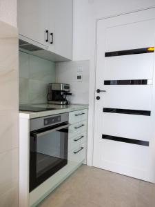Bileća的住宿－Aurora studio - Bileca，厨房配有白色橱柜、炉灶和门。
