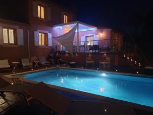 a swimming pool in front of a house at night at Superbe Villa avec piscine - vue mer - Presqu'Île de Giens - 5 étoiles in Hyères