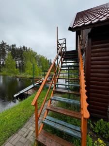 a wooden staircase leading to a building next to a river at Vasaras māja Rāzna - Pirts 