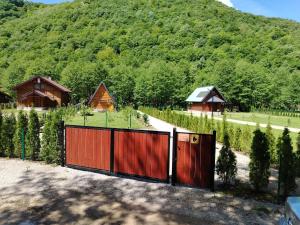 a red fence in front of a hill with houses at Vikendica Raj in Bihać