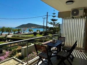 a table and chairs on a balcony with a view of the water at Seashore Happiness Apartments in Porto Rafti
