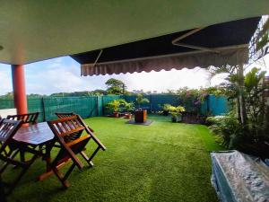 a patio with two chairs and a table on a lawn at TAHITI - Amoe Condo in Mahina