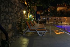 a row of lounge chairs next to a pool at night at Sarıhan Apart Otel in Oludeniz