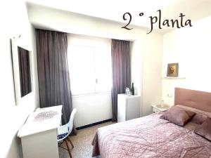 a bedroom with a bed and a desk and a window at Escondite central con terraza compartida en la azotea in Roses
