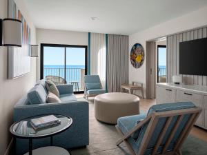 a living room with a couch and chairs and a television at Grand Cayman Marriott Resort in George Town