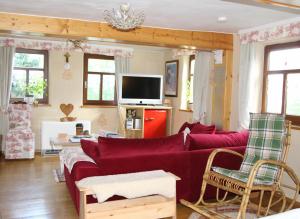een woonkamer met een rode bank en een tv bij Pension Rhöner Kräuterwerk 